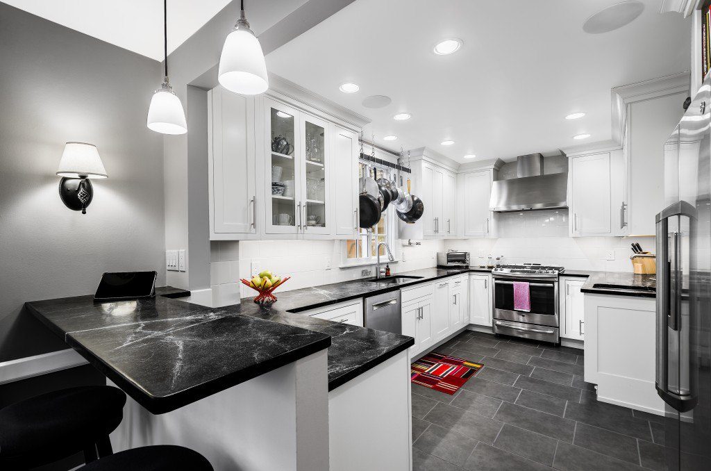 A traditional kitchen design with white cabinets, dark granite counter-tops, and stainless-steel appliances. Baker's rack over window.