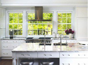 White kitchen with hood in front of a window 