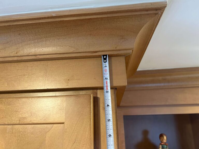 Light Maple shaker cabinetry with two piece crown molding. Second Photo shows tape measuring size of riser at 2.5 inches