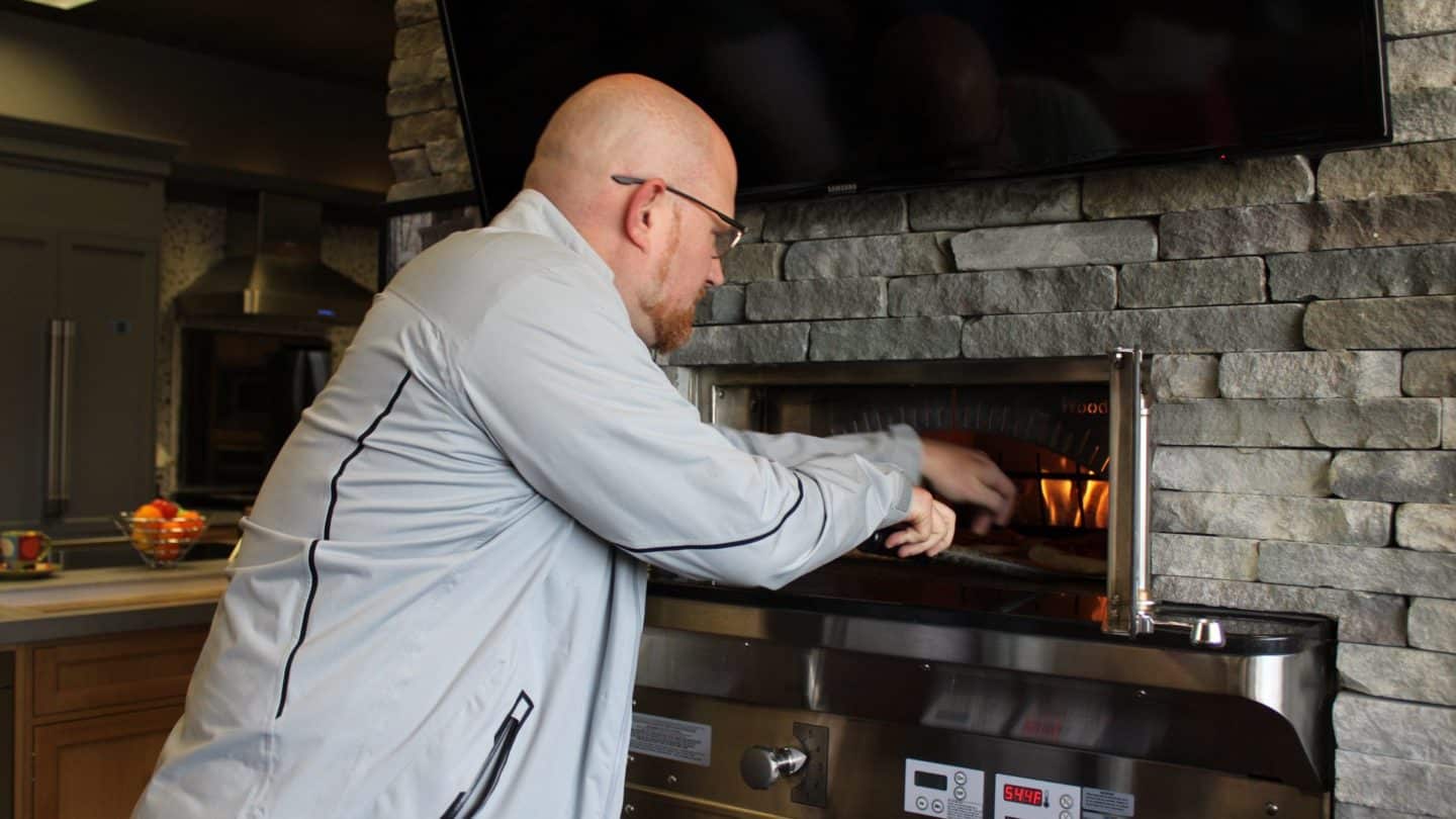 Man putting pizza in oven