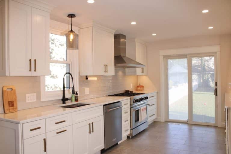 White kitchen with shaker style cabinets, stainless steel appliances, and a stainless steel oven hood