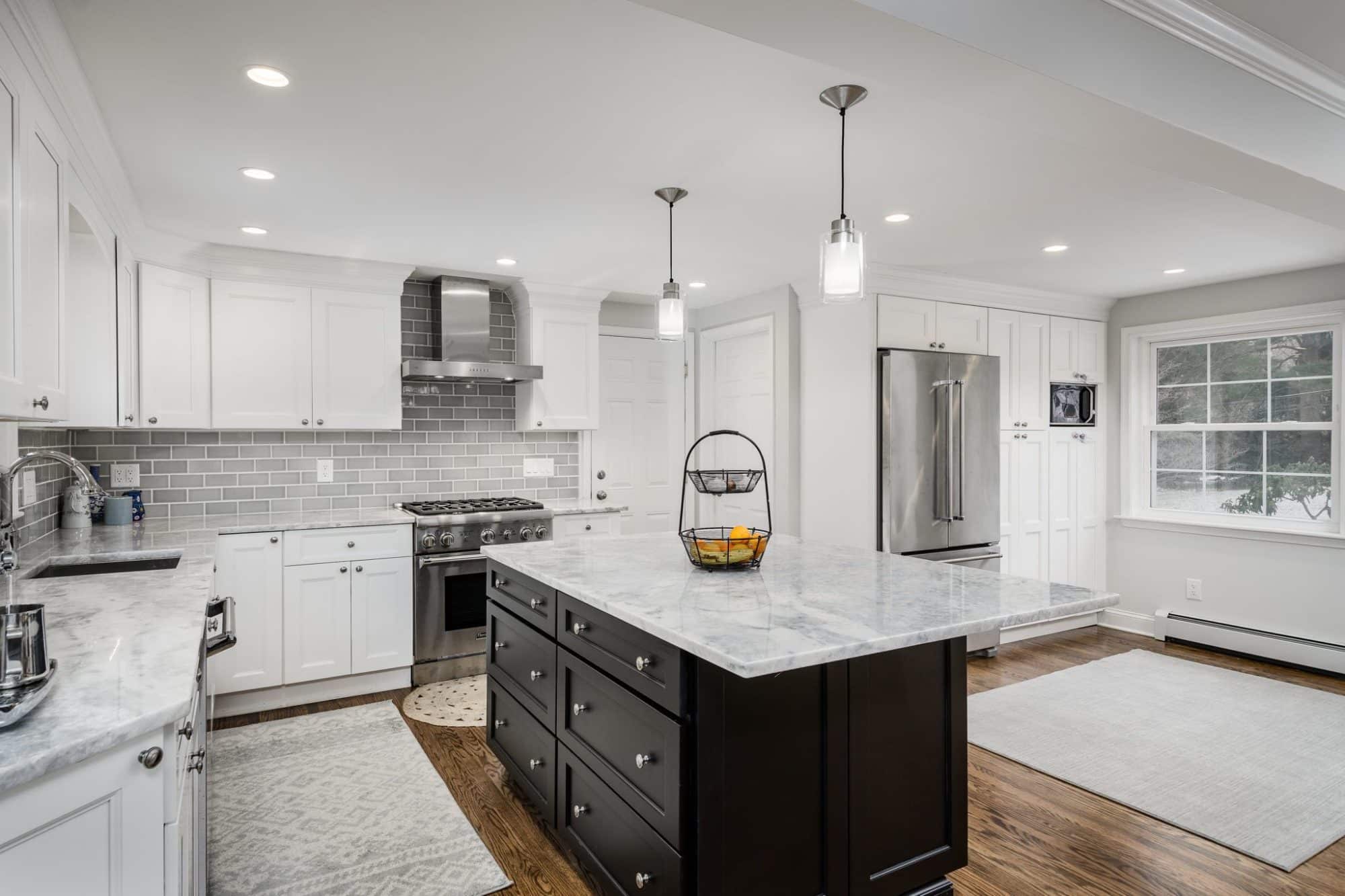 white kitchen with dark island. The compromise in this kitchen was the placement of the refrigerator.