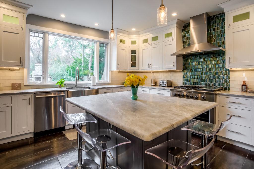 white L shape kitchen with small island and 2 different backsplash colors 