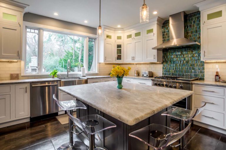 Kitchen island with light grey marble countertops and countertop seating.