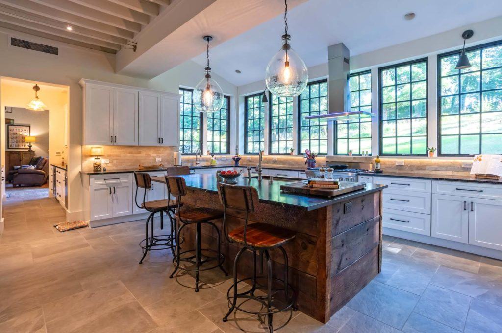 Big barn house kitchen with lots of natural light, windows and a big wooden island. Designed in highly ranked Fabuwood cabinet brand.