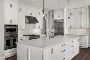 Beautiful kitchen in new luxury home addition with island, pendant lights, and hardwood floors. Features stainless steel appliances, including double oven, refrigerator, gas range and hood.